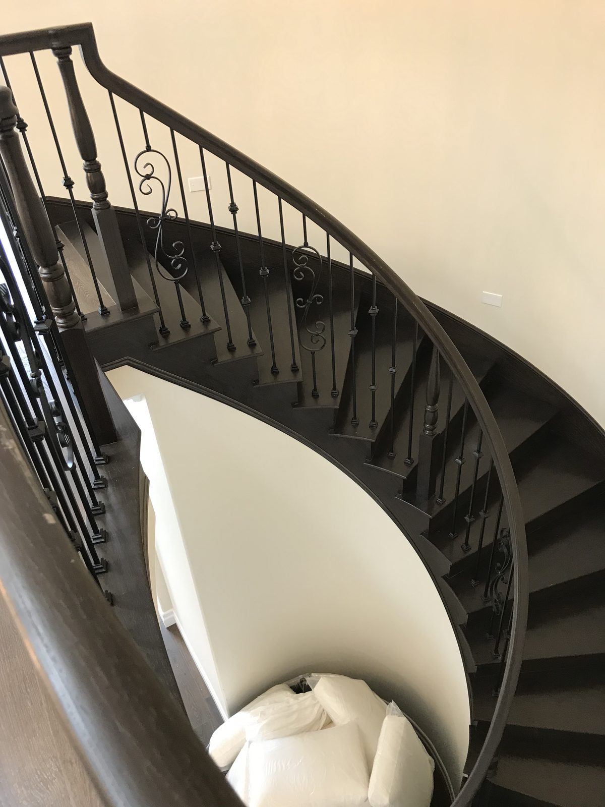 Custom curved interior staircase with custom iron balusters built by Newport Construction Group